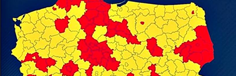 Na ilustracji: kolorowa mapa Polski na niebieskim tle. Polska z podziałem na powiaty w kolorach żółtym i czerwonym.