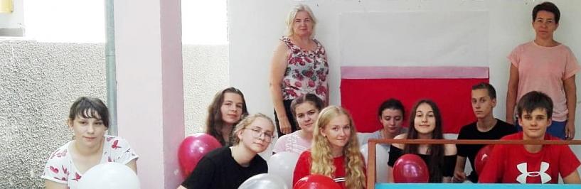 Bielska młodzież w Mołdawii na tle polskiej flagi