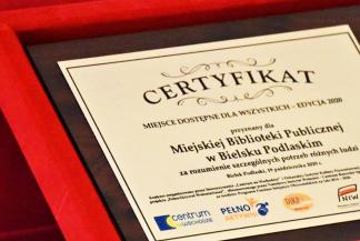 Ilustracja przedstawia grawerton - certyfikat miejsca dostępnego dla wszystkich przyznany Miejskiej Bibliotece Publicznej w Bielsku Podlaskim